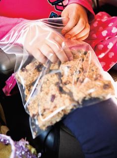 a woman sitting in a car seat holding a bag of granola