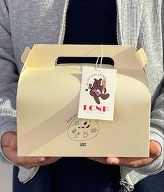 a person holding up a box with a tag on it's front and side