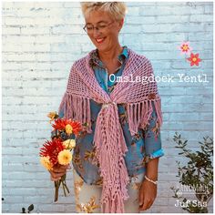 an older woman wearing a pink shawl with flowers on it and holding a bouquet