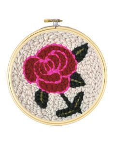 a close up of a embroidery on a white surface with a pink rose in the center