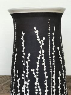 a black and white vase sitting on top of a wooden table