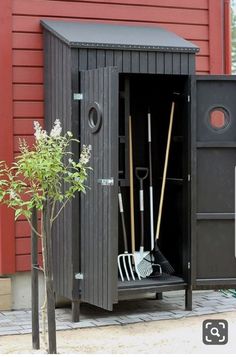 an outdoor storage shed with shovels and rakes in it