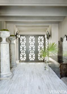 a white room with two large vases and a plant on the floor in front of it