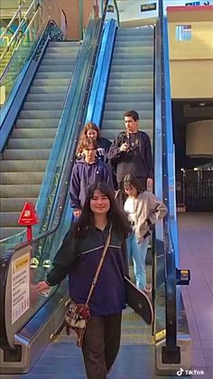 four people are riding an escalator with their dog on the leash and one person is walking up