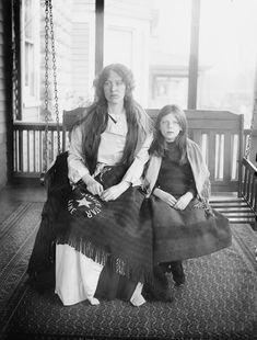 an old black and white photo of two women sitting on a porch swing with their arms around each other