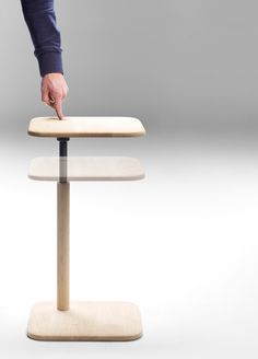 a person standing on top of a wooden stand with their hand over the edge of it