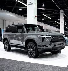 an suv is on display in a showroom with other cars behind it and people standing around