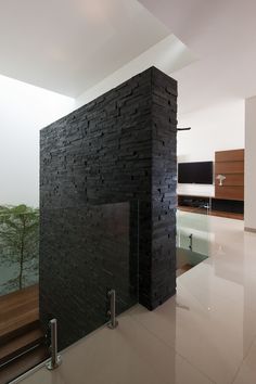 a black brick wall in the middle of a room with stairs leading up to it