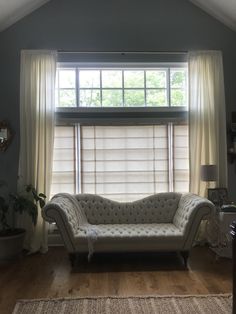 a couch sitting in front of a window next to a rug on top of a hard wood floor