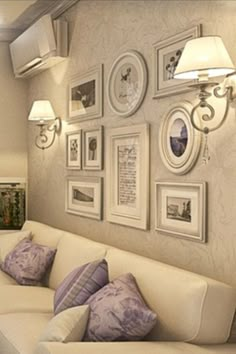 a living room with white couches and pictures on the wall above them, along with two lamps