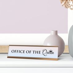 there is a vase with flowers in it next to a sign that says office of the queen