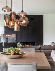 a dining room table and chairs with lights hanging from the chandelier above it