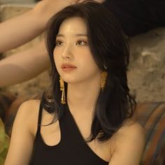 a woman sitting on top of a couch wearing gold earrings