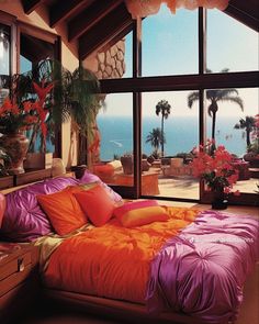 a bedroom with a large window overlooking the ocean and palm trees on the other side