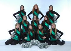 a group of cheerleaders posing for a photo in their green and black outfits