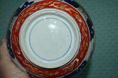 a hand holding a red and blue bowl