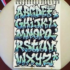 a spiral notebook covered in graffiti on top of a table