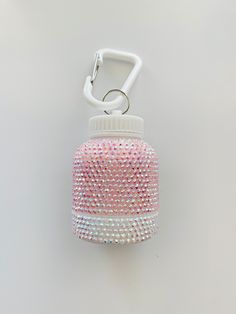 a bottle shaped keychain with pink and white sequins on the side