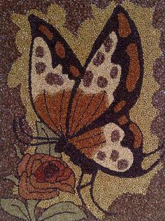 a close up of a butterfly and flower on a mosaic tile wall in a bathroom