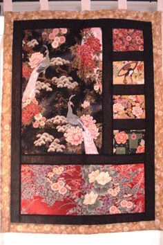 a quilted wall hanging on the side of a window with flowers and birds in it