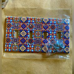 a decorative light switch plate cover with blue and red designs on it's side