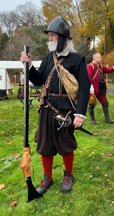 an old man dressed in period clothing holding a stick