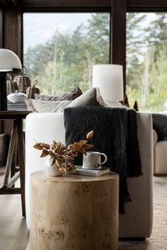 a wooden table sitting in front of a window next to a white couch and chair