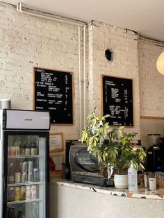 a coffee shop with menus on the wall and a plant in front of it