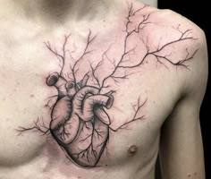 a man's chest with a heart and tree branches tattoo on his chest is shown