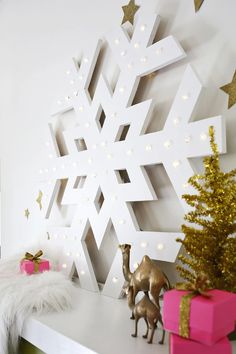 a white shelf topped with toys and a snowflake on top of it next to a christmas tree