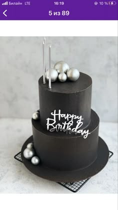 a three tiered black cake with silver balls on top