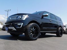 a black truck parked in a parking lot next to other cars and trucks behind it