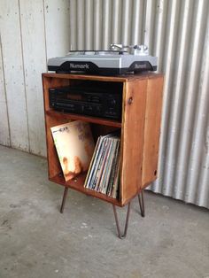 an old record player is sitting on top of a wooden shelf with cd's