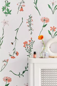 a white cabinet sitting next to a wall with flowers painted on the walls and in front of it