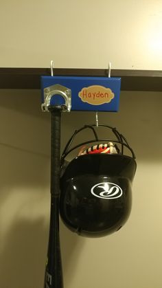 a baseball bat and helmet hanging from a hook on a wall with a sign that says hayden