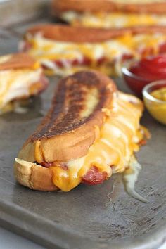 two hot dogs with cheese and ketchup are on a baking sheet, ready to be eaten