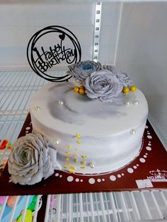 a white cake with flowers on it and a happy birthday sign