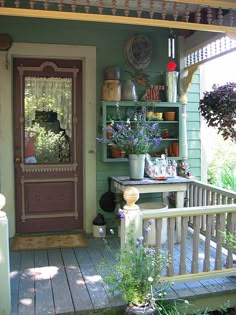 the front porch is decorated with flowers and pots on it's shelf, along with potted plants