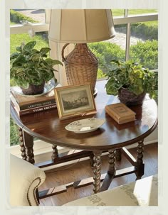 a table with some books and plants on it in front of a window that looks out onto the yard