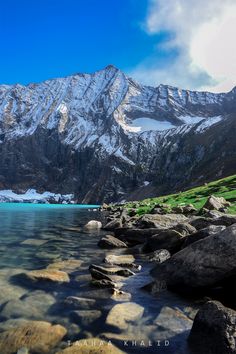 the mountain range is covered in snow and green grass, as well as some rocks