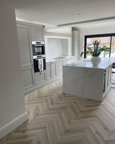 a large kitchen with an island in the center and white cabinets on both sides, along with hardwood flooring