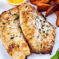 two fish fillets on a white plate next to sweet potato wedges and carrot sticks