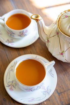 two tea cups and saucers on a wooden table