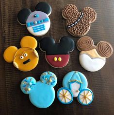 mickey mouse cookies are arranged on a wooden table with other decorated cookies in the shape of disney's ears