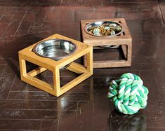 a wooden box with a metal bowl on the floor next to it and a green rope ball