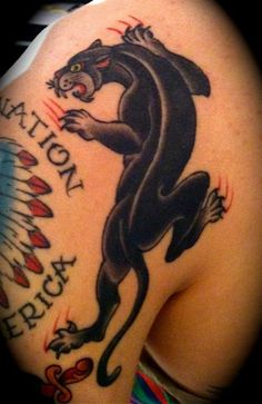 a black panther tattoo on the back of a woman's shoulder and arm, with words written below it