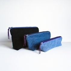 two blue and black bags sitting next to each other on a white surface with one bag in the middle