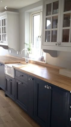 a large kitchen with wooden floors and white cupboards on the wall, along with an island