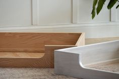 a wooden box sitting on top of a carpeted floor next to a potted plant