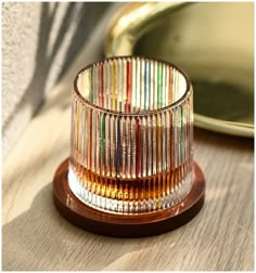 a glass cup sitting on top of a wooden table next to a gold platter